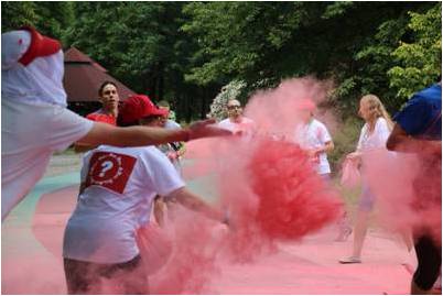ludzie obsypują biegnących chmurą różowego pyłu
