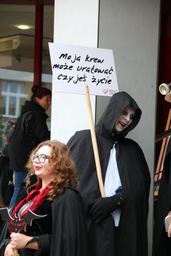 Zdjęcie: mężczyzna przebrany za wampira trzyma transparent z napisem: "Moja krew może uratować czyjeś życie"